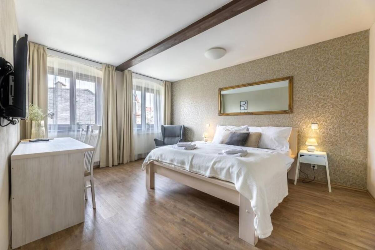 Une chambre à coucher comprenant un lit, une table de chevet, une chaise, un bureau et un téléviseur.