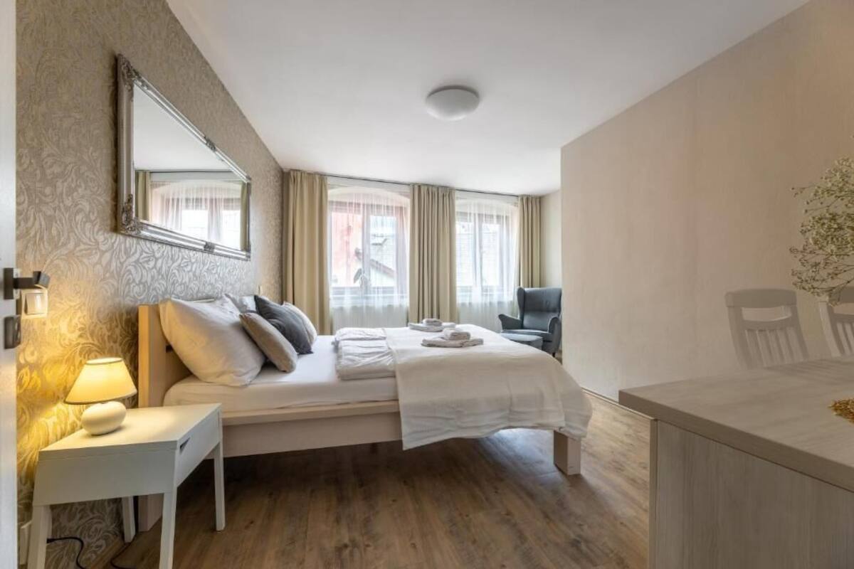 Une chambre d’hôtel avec un lit, un bureau, une chaise, un miroir et une fenêtre avec des rideaux.