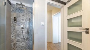A bathroom with patterned tiles and a shower area. - Apartmány U Pavla (Cesky Krumlov)