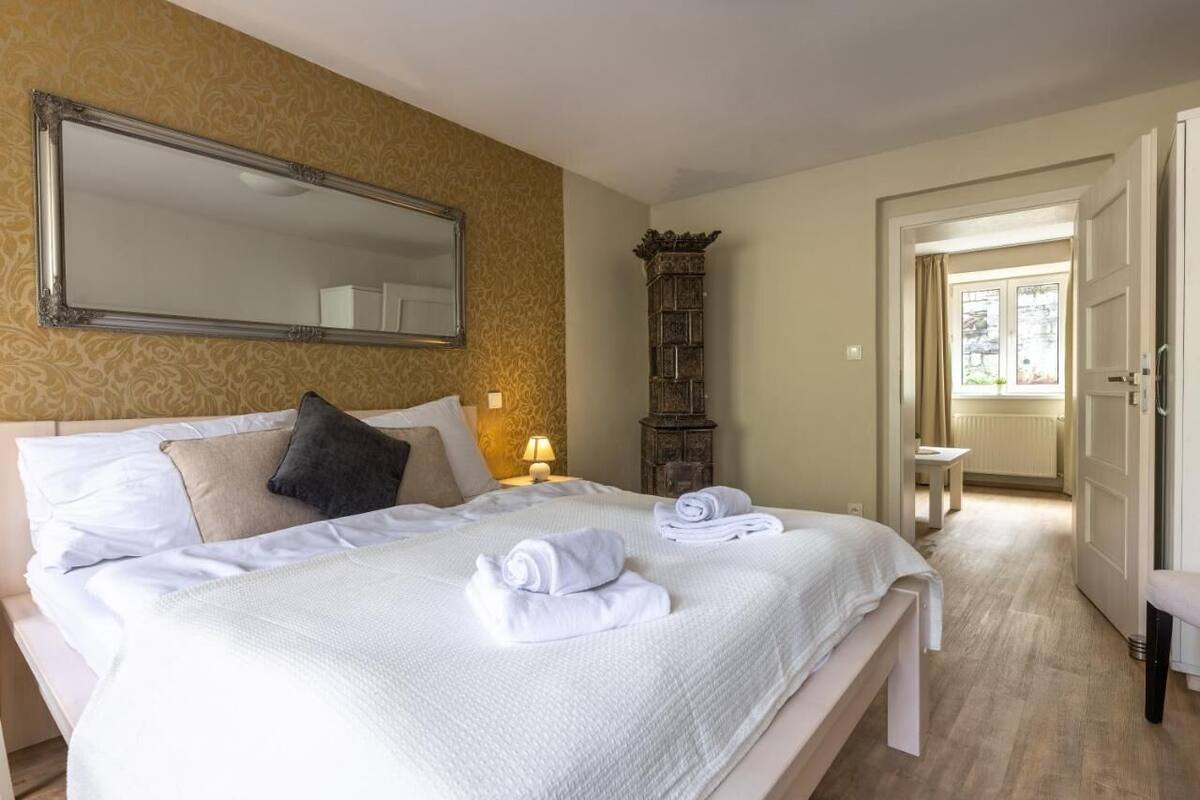 Une chambre d’hôtel avec un grand lit, un miroir, une armoire en bois et vue sur la salle de bain.