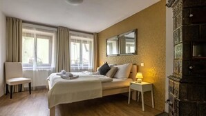 A hotel room with a bed, bedside table, lamp, chair, and a large ornate cabinet. - Apartmány U Pavla (Cesky Krumlov)