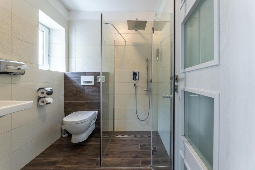 A modern bathroom with a glass-enclosed shower, a toilet, and a bathtub.