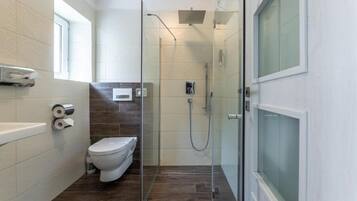 A modern bathroom with a glass-enclosed shower, a toilet, and a bathtub.