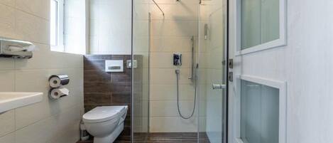 A modern bathroom with a glass-enclosed shower, a toilet, and a bathtub.