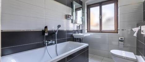 Un baño moderno con una bañera grande, un inodoro y un lavamanos.
