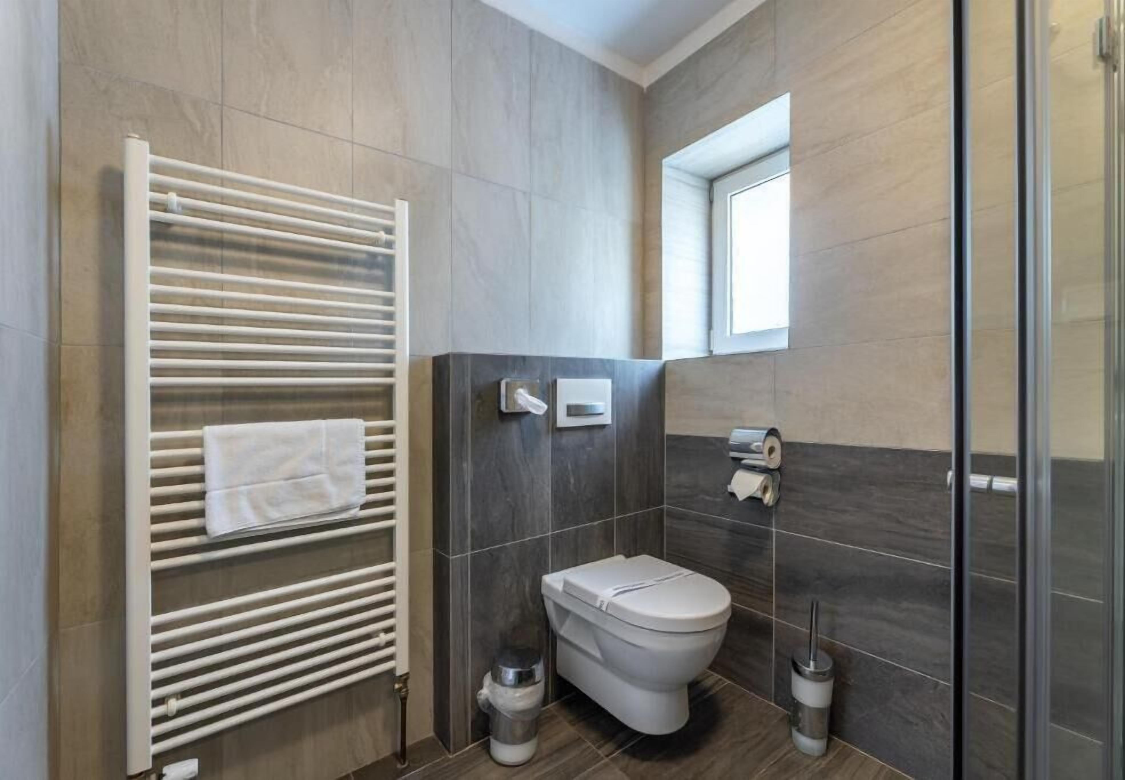 Een moderne badkamer met een ingebouwd toilet, een handdoekhouder, een handdroger en een douchecabine van glas.