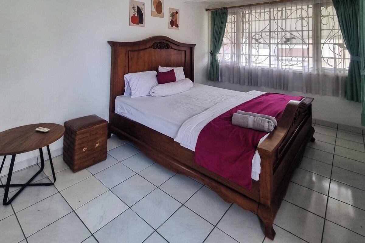 A bedroom with a wooden bed, a small round table, and a nightstand.