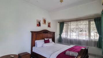 A bedroom with a wooden bed, a small round table, and a nightstand.