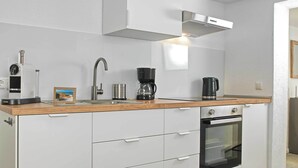 A modern kitchen with white cabinetry, a wooden countertop, a built-in oven, and a stainless steel range hood. - "Ankerplatz" Vacation Rental with a Terrace Between Wismar and the Island of Poel (Groß Strömkendorf)