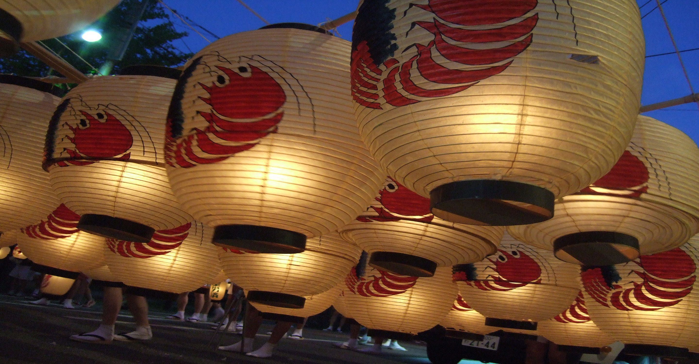 Una serie de farolillos de papel iluminados, con diseños rojos y blancos, probablemente parte de una exhibición cultural o festiva.