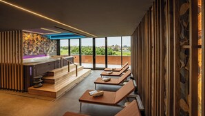 Ein moderner Lounge-Bereich mit Holzbänken, einer Steinwand und Blick ins Freie.