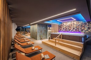 Een moderne spa met houten banken, een jacuzzi en een stenen muur.