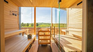 Eine Sauna mit Holzsitzen und einer Glaswand mit Blick auf eine grüne Landschaft.