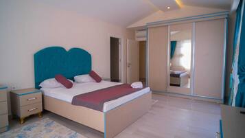 A bedroom with a large bed, a bedside table, a wardrobe, and a mirror.
