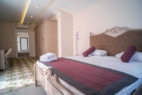 A hotel room with a large bed, a wardrobe, a desk, and a bathroom door. - Graf Victor Apart Hotel (Alanya)