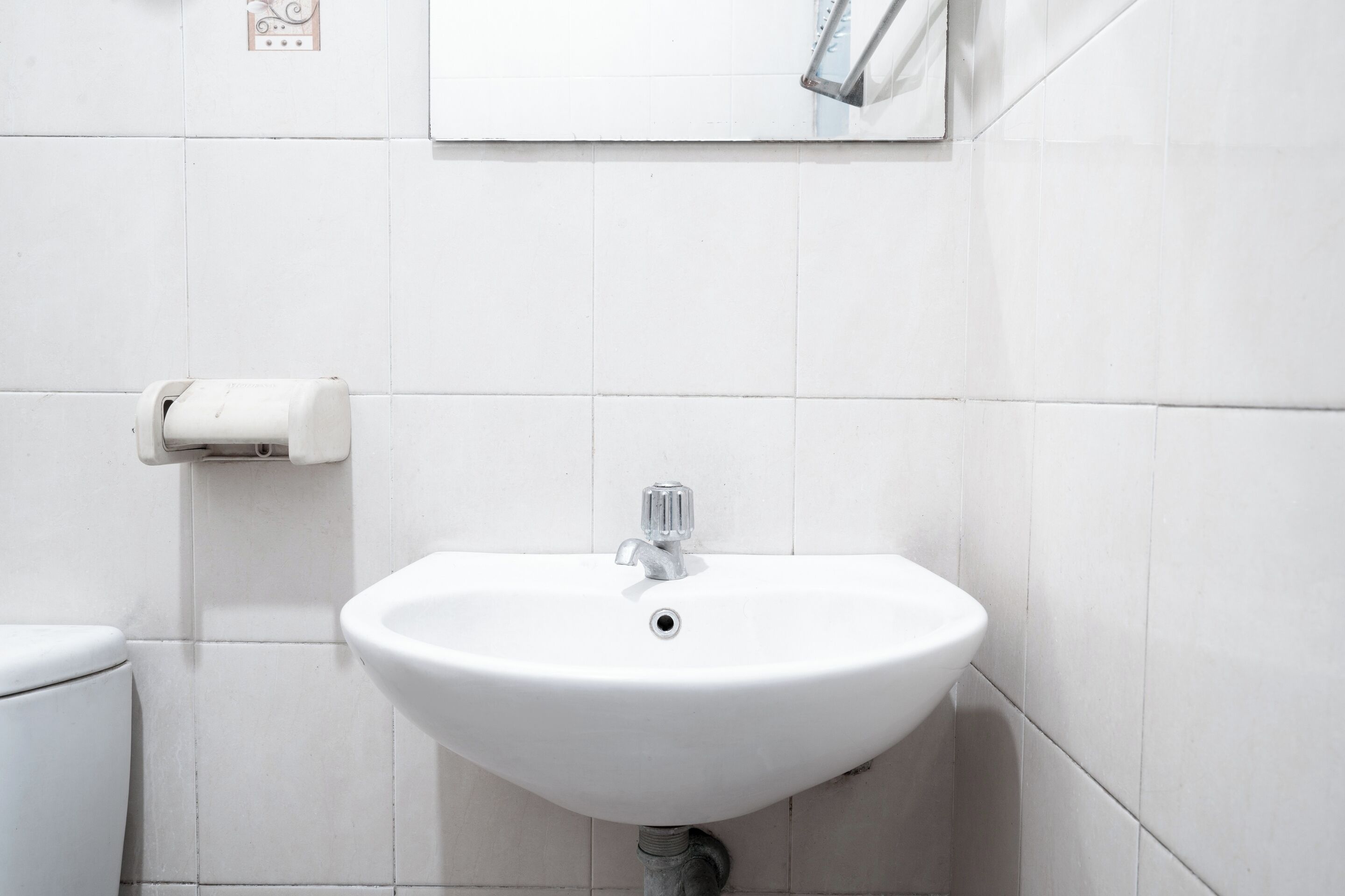 A white bathroom with a sink, toilet, and a hand dryer.