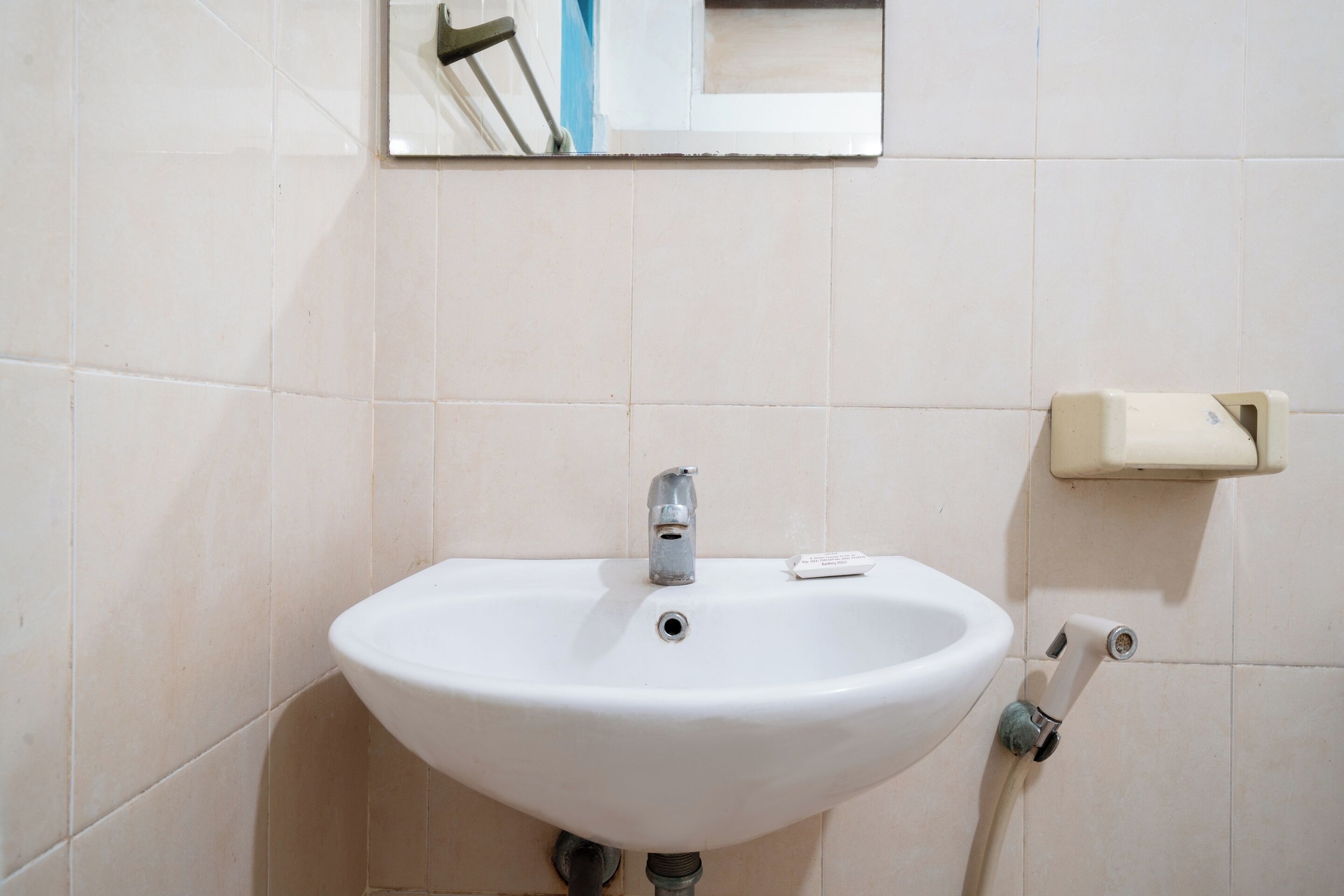 A white bathroom sink with a mirror above it, a soap dispenser, and a towel rack.