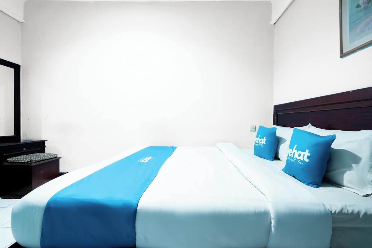 A hotel room with a bed, a nightstand, and a wall-mounted TV.