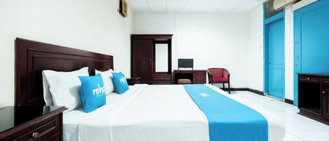 Una habitación de hotel con una cama grande, un escritorio, una silla y un armario.