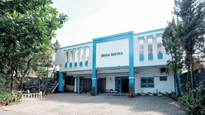 A building with a sign reading "GRAMA SARTIKA" and a paved entrance area with potted plants. - Sartika Hotel (Bandung)
