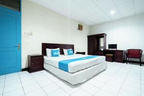 Una habitación de hotel con una cama grande, un escritorio, una silla y un armario.