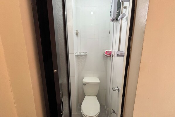 Un bagno piccolo e stretto con il water bianco, una zona doccia e un appendi asciugamani.