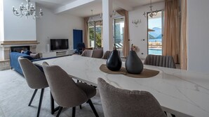 A spacious living room with a large white marble table, comfortable seating, a fireplace, and a view of the sea. - 4-bedroom villa in wonderful Strp, Kotor with WiFi, fitness room (Strp, Kotor)