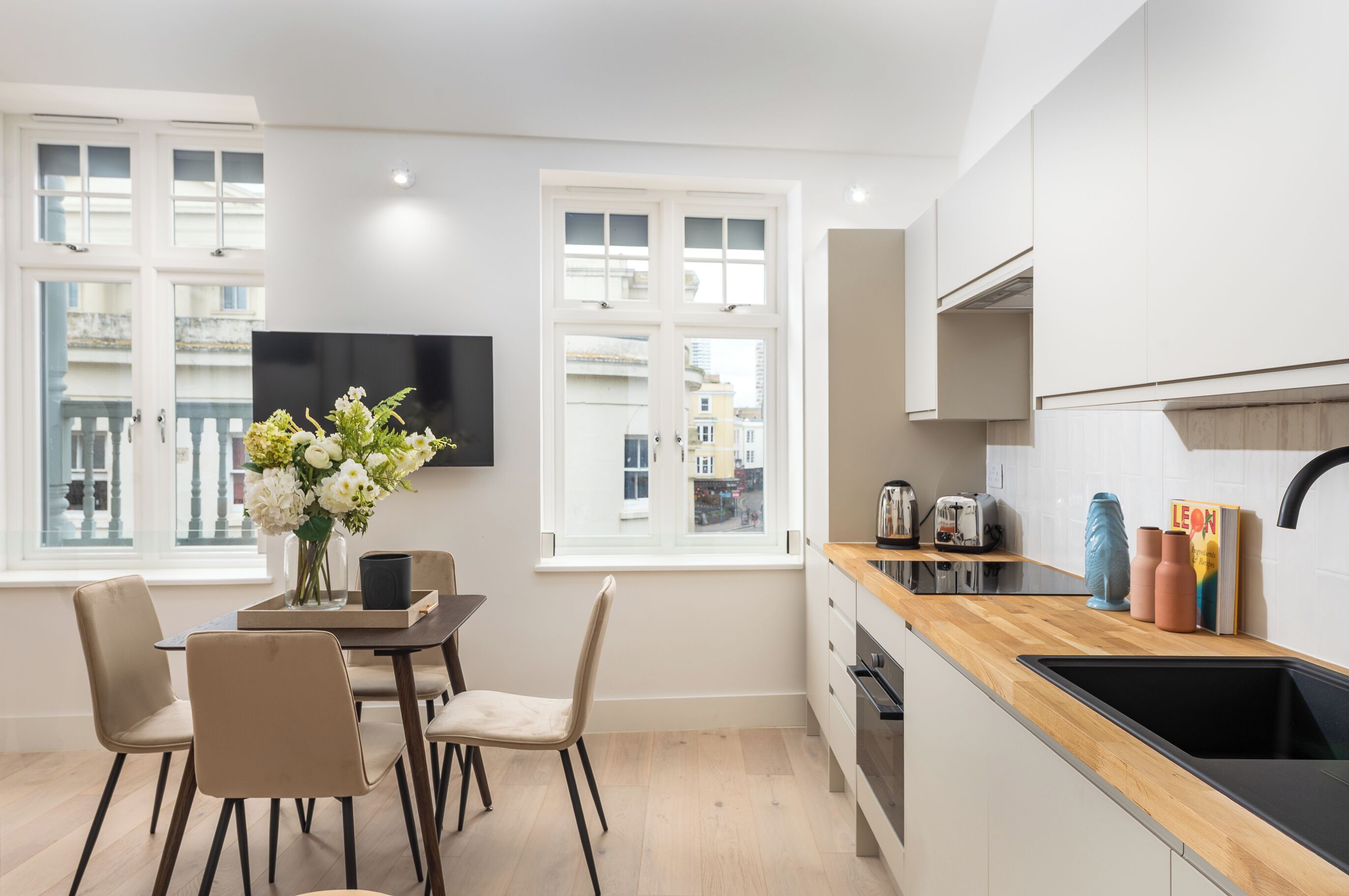 Una cocina moderna con encimera de madera, un lavamanos negro y un comedor con mesa y sillas.