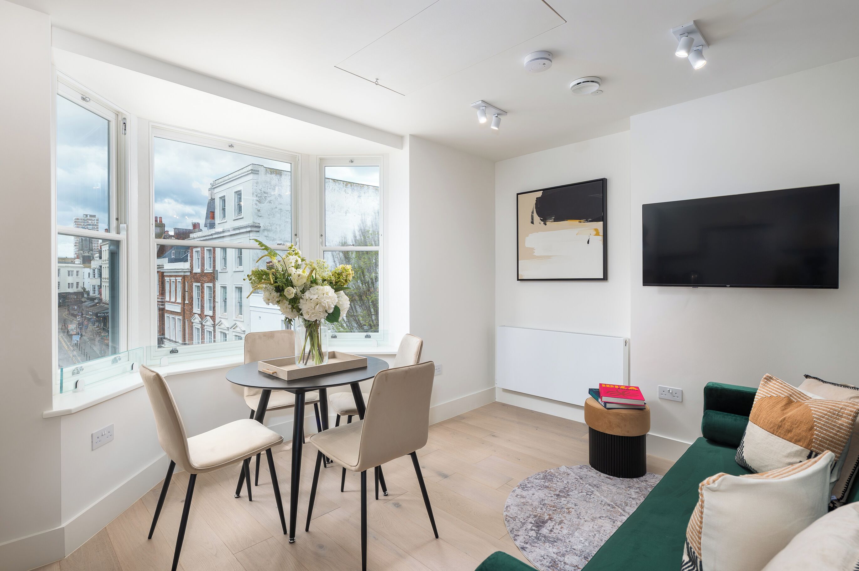 Un salon moderne avec un coin repas, de grandes fenêtres offrant une vue sur la ville, un téléviseur à écran plat et un coin salon confortable.
