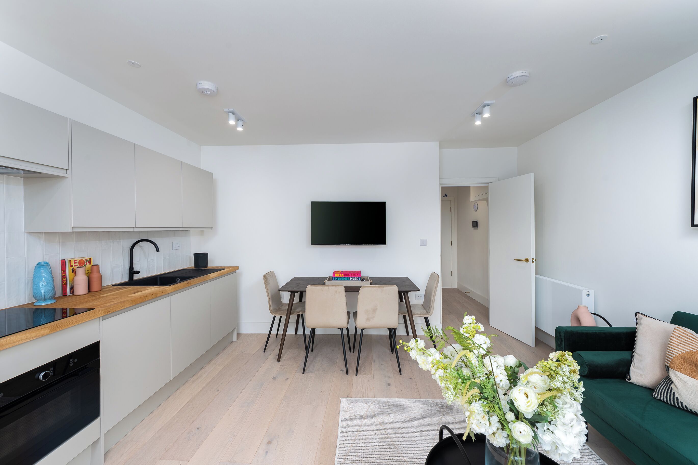 A modern kitchen with white cabinets, a black countertop, and a built-in dishwasher.