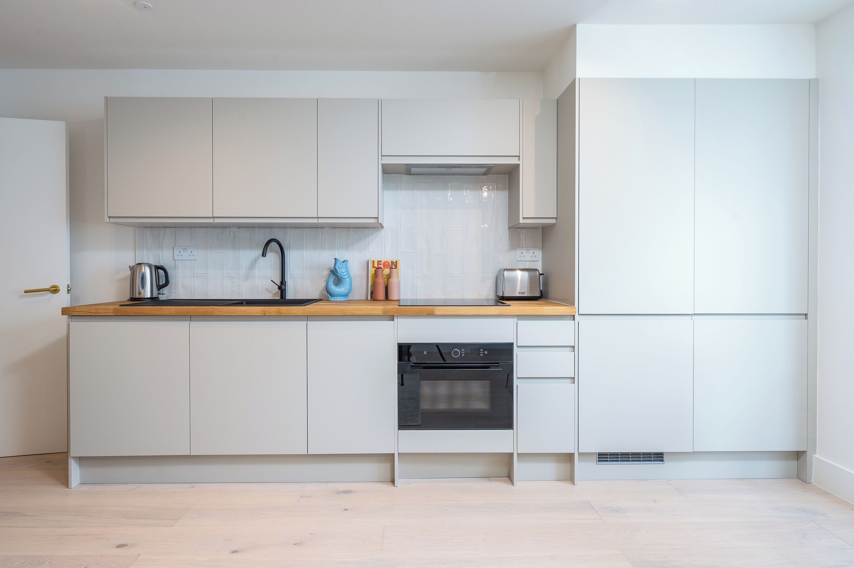Een moderne keuken met witte kasten, een houten aanrecht en een ingebouwde oven.
