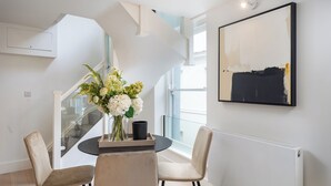 Un espace repas moderne avec une table ronde, deux chaises, un vase de fleurs et un escalier.