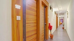 A hotel hallway with wooden doors, numbered 107, and a potted plant.