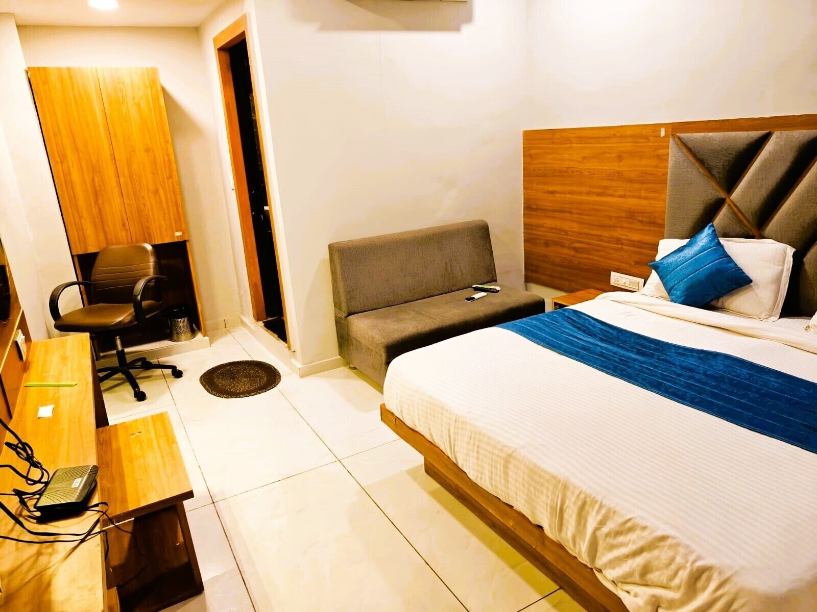 Una habitación de hotel con cama, escritorio, silla y armario.
