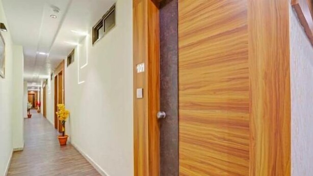 A hallway with wooden doors, a potted plant, and a number sign.