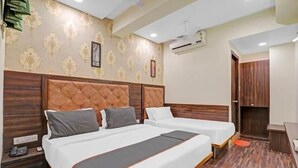 A hotel room with two beds, a wooden headboard, a patterned wall, and an air conditioning unit.