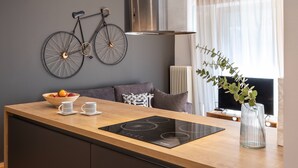 A modern kitchen with a wooden countertop, a black induction cooktop, a bowl of fruit, and a bicycle mounted on the wall.