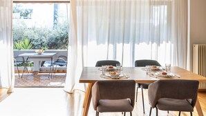 A dining area with a table set for four, a view of the outdoors, and a window with sheer curtains.