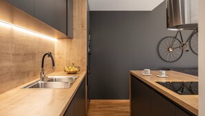 A modern kitchen with wooden countertops, stainless steel sink, and a bicycle mounted on the wall.
