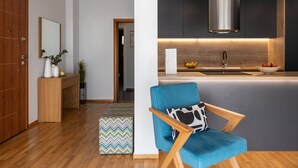 A modern kitchen with a central island, wooden flooring, and a blue chair with a wooden frame.
