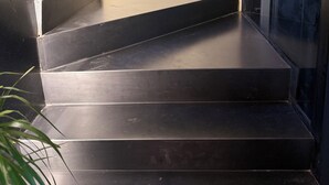 Un juego de escaleras de metal negro que conducen a un ascensor de vidrio.