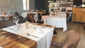 Un restaurante con mesas dispuestas para comer, que presenta mesas de madera y sillas con cojines.