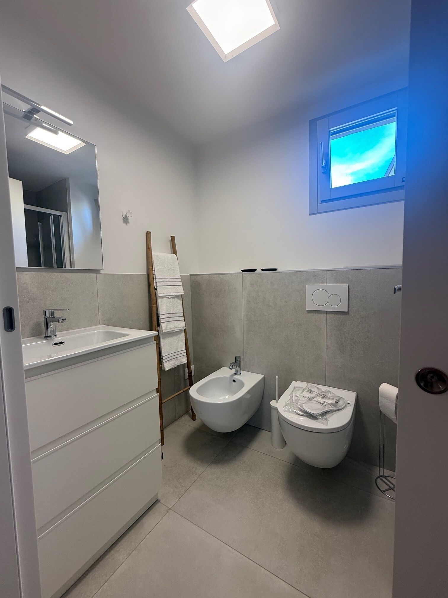 Un bagno moderno con bidet, WC e uno specchio grande.