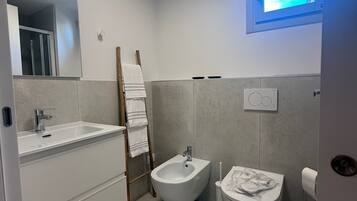 Un bagno moderno con bidet, WC e uno specchio grande.