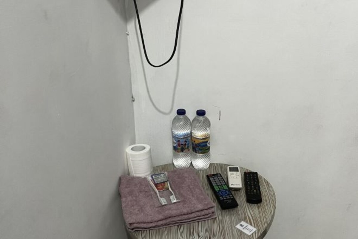 A small round table with a towel, remote controls, a mobile phone, and two water bottles.