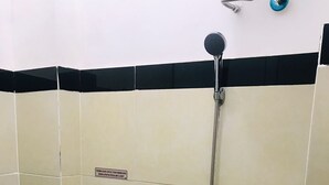 A small bathroom with a toilet, a shower, and a sign on the wall. - Ez Door (Yogyakarta)