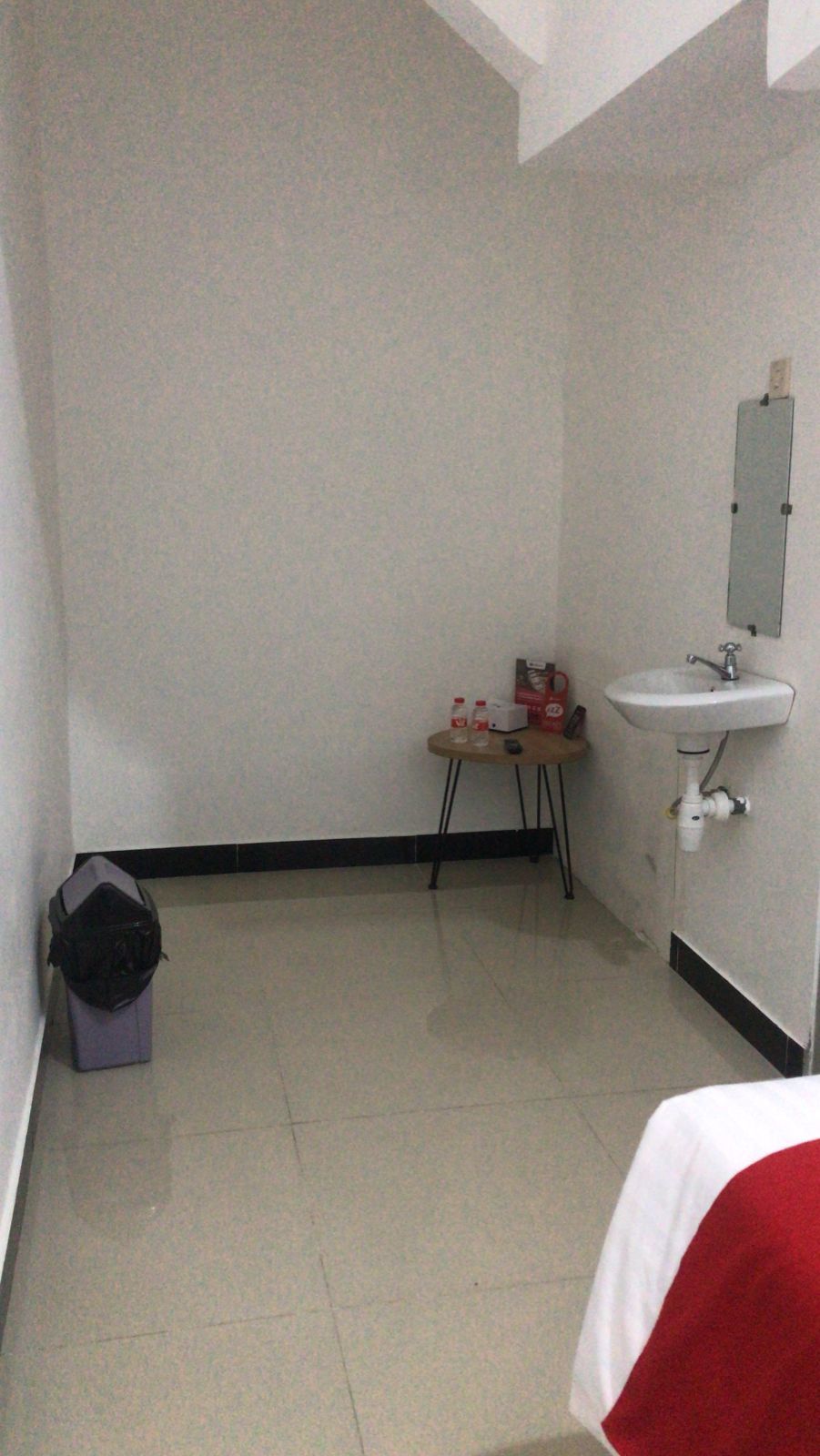A small, clean bathroom with a white sink, a mirror, and a small table with toiletries.