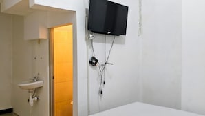 A hotel room with a bed, a mounted television, an air conditioning unit, a sink, and a door leading to another room. - Ez Door (Yogyakarta)
