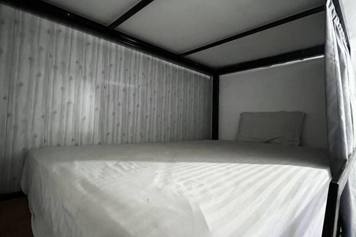 A single bed in a room with a striped wall and a plain ceiling.