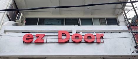 Un edificio con un letrero que dice "ez Door" y varias unidades de aire acondicionado instaladas en el exterior.